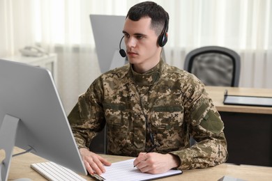 Military service. Young soldier in headphones working at table in office