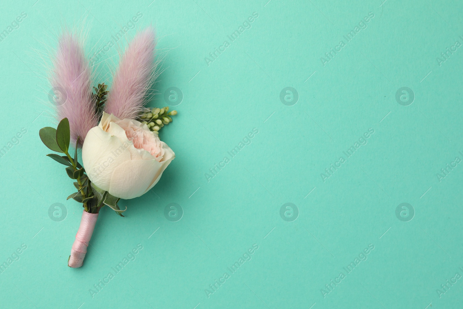 Photo of Small stylish boutonniere on turquoise background, top view. Space for text