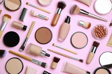 Face powders and other decorative cosmetic products on pink background, flat lay