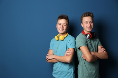 Teenage twin brothers with headphones on color background. Space for text