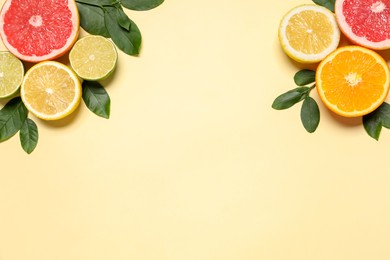 Photo of Different cut citrus fruits and leaves on beige table, flat lay. Space for text