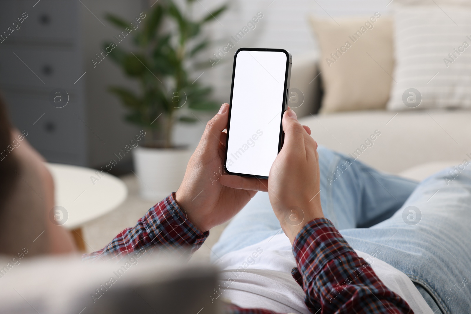 Photo of Man using mobile phone on sofa at home, closeup