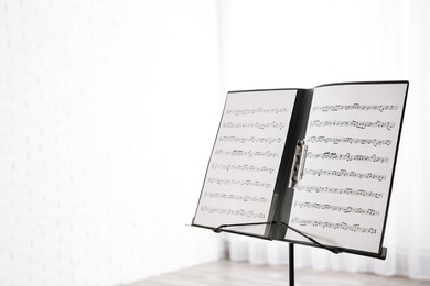 Photo of Note stand with music sheets indoors. Space for text