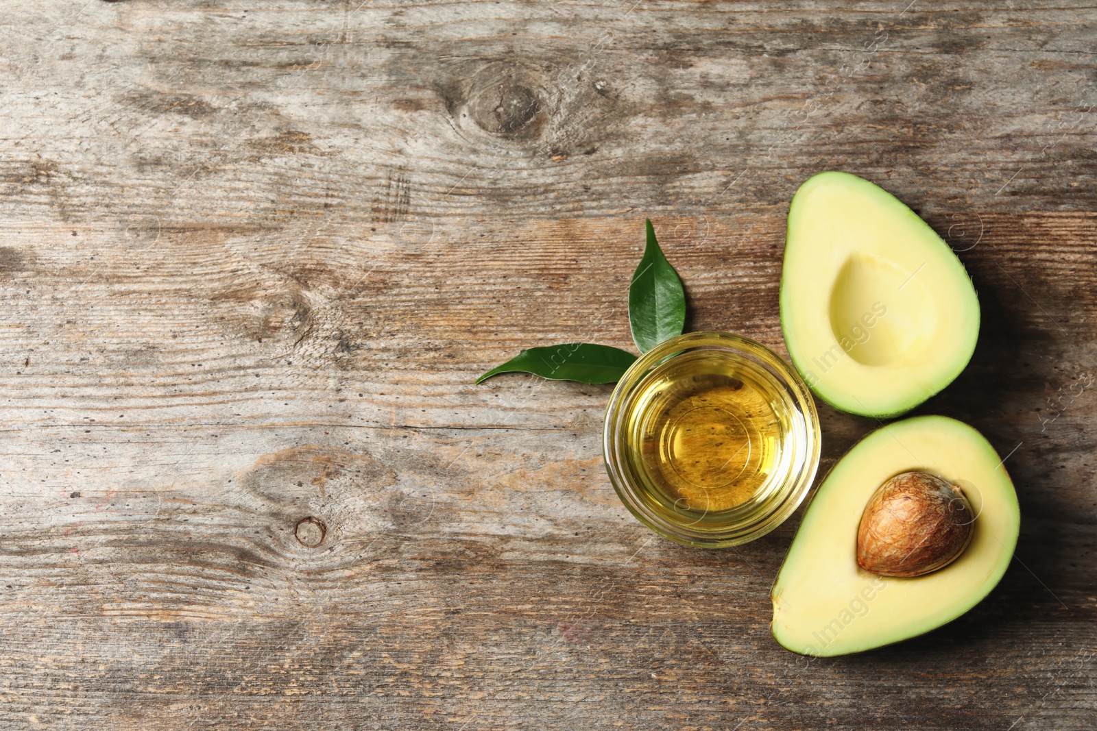 Photo of Gravy boat with oil and ripe fresh avocado on wooden table, top view