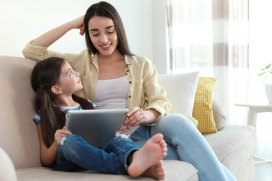 Mother and daughter reading E-book together at home