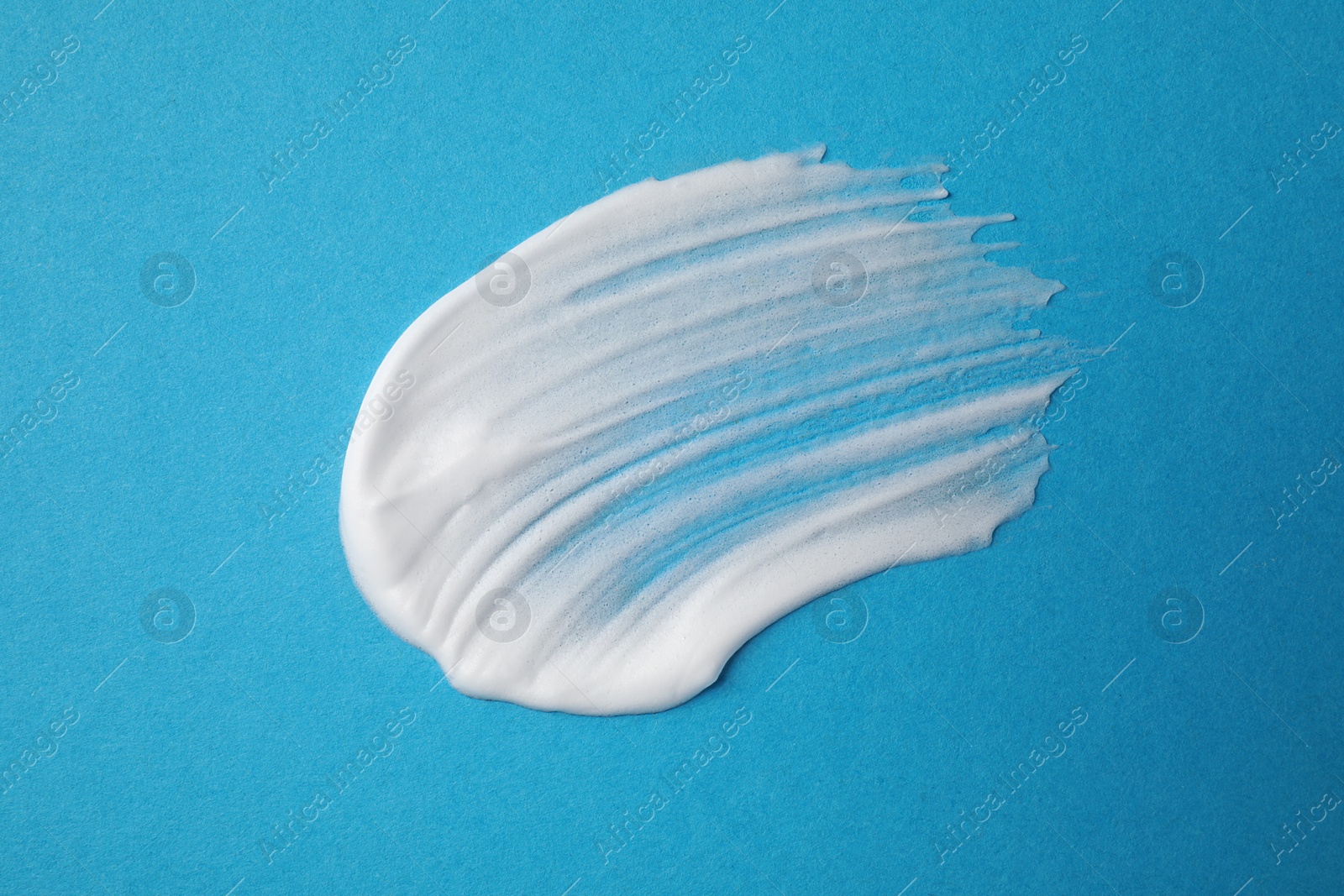 Photo of Sample of shaving foam on blue background, top view