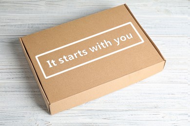 Image of Roles and responsibilities concept. Closed cardboard box with text It stars with you on white wooden table