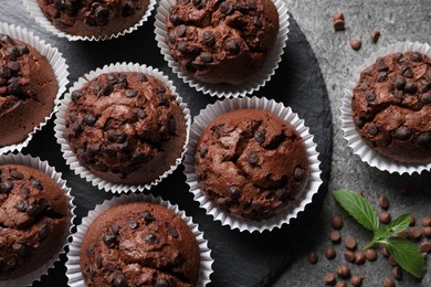 Photo of Tasty chocolate muffins on grey textured table, flat lay
