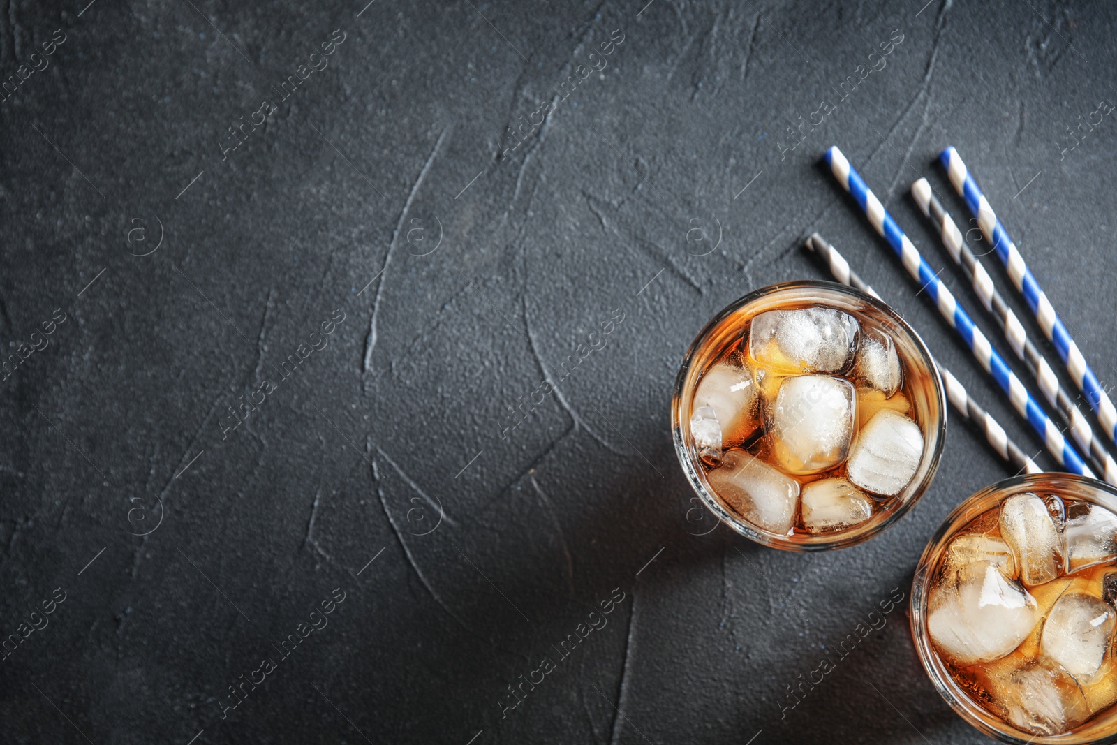 Photo of Glasses of refreshing cola with ice cubes on grey background, top view. Space for text