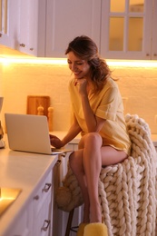Photo of Beautiful young woman with laptop in kitchen. Weekend morning