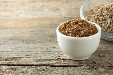 Photo of Caraway (Persian cumin) powder and dry seeds on wooden table, space for text