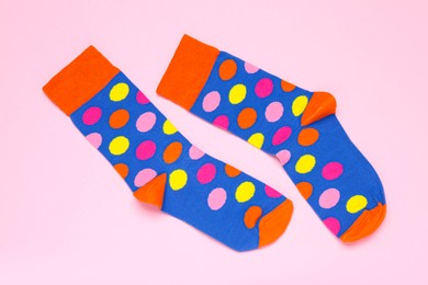 Photo of Pair of colorful socks on light pink background, flat lay