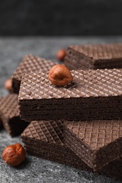 Delicious chocolate wafers and hazelnuts on grey table, closeup