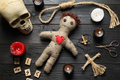 Flat lay composition with voodoo doll on dark wooden table