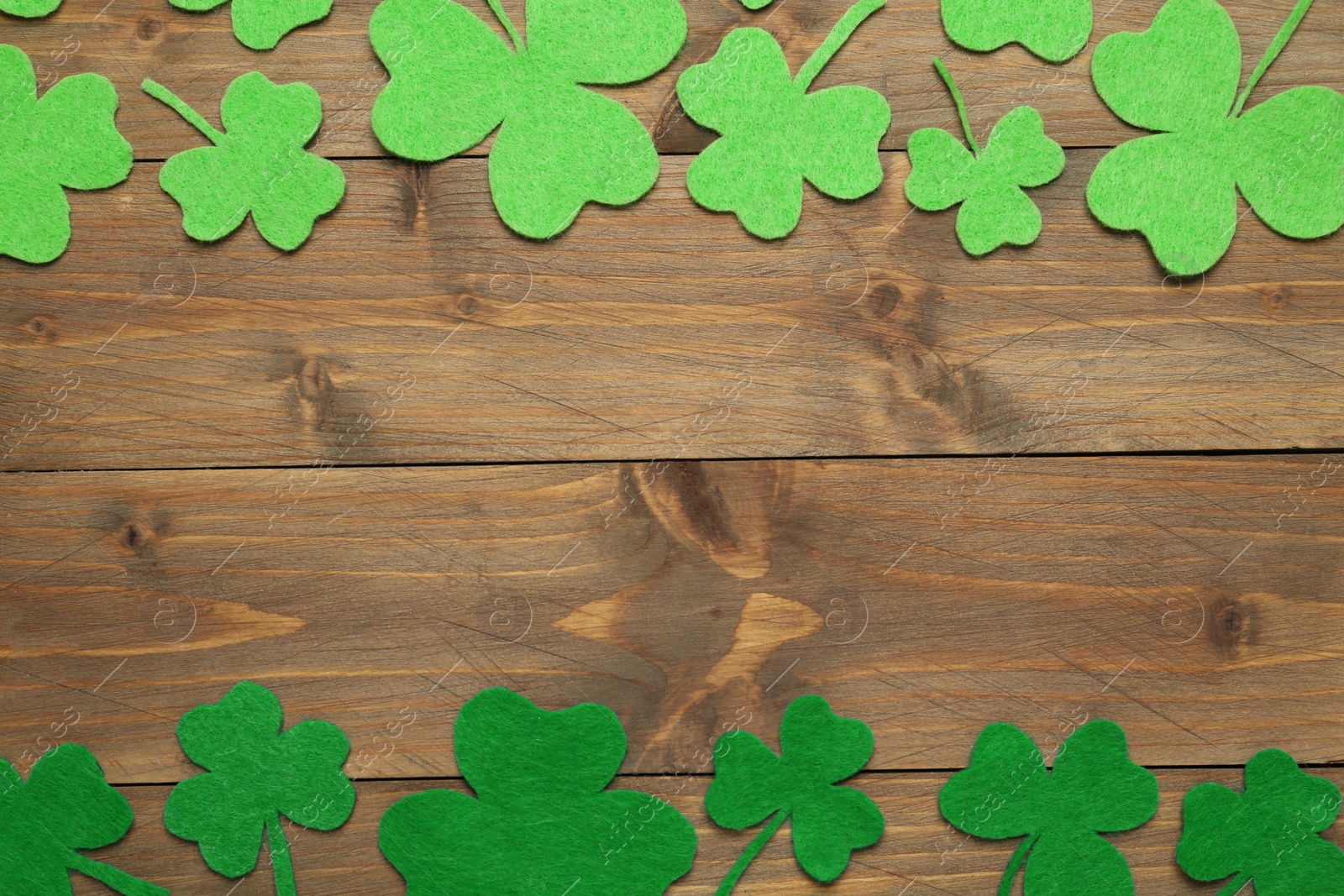 Photo of Decorative clover leaves on wooden background, flat lay with space for text. St. Patrick's Day celebration