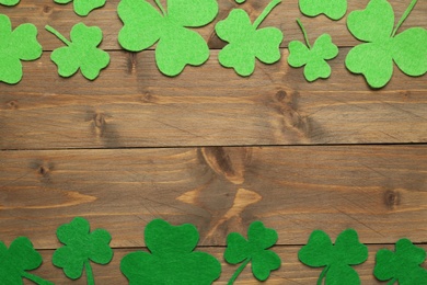 Decorative clover leaves on wooden background, flat lay with space for text. St. Patrick's Day celebration