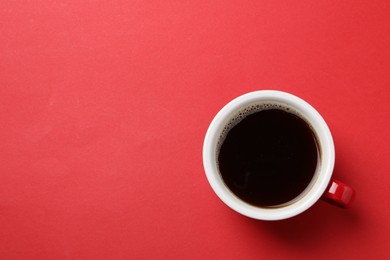 Photo of Aromatic coffee in cup on red background, top view. Space for text