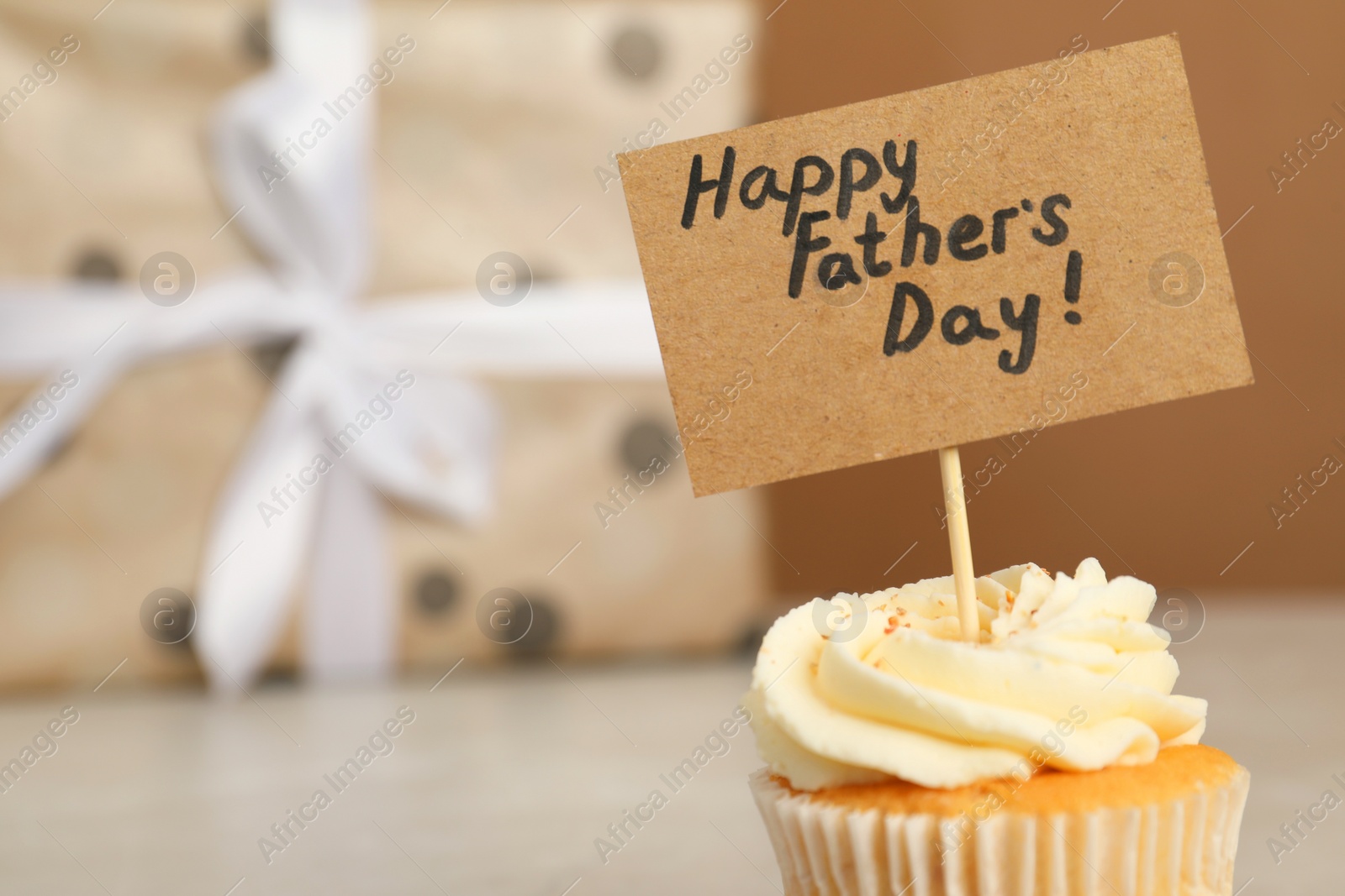 Photo of Happy Father's Day. Tasty cupcake with greetings on blurred background, closeup. Space for text