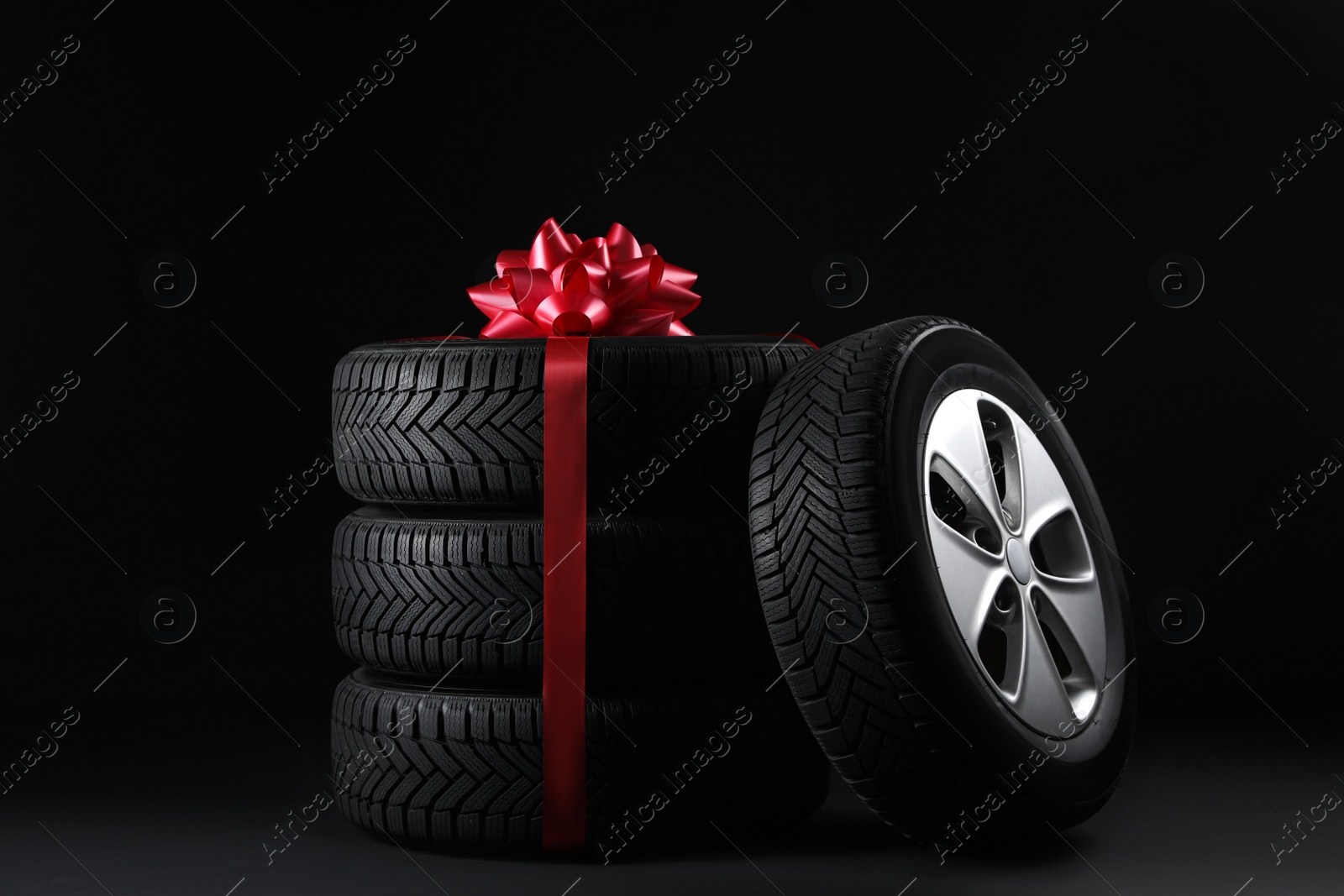 Photo of Gift set of wheels with winter tires on black background