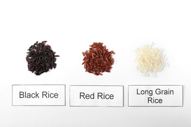 Photo of Different types of uncooked rice and cards on white background, top view
