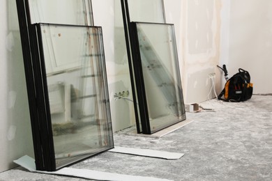 Double glazing windows on floor near plasterboard wall indoors