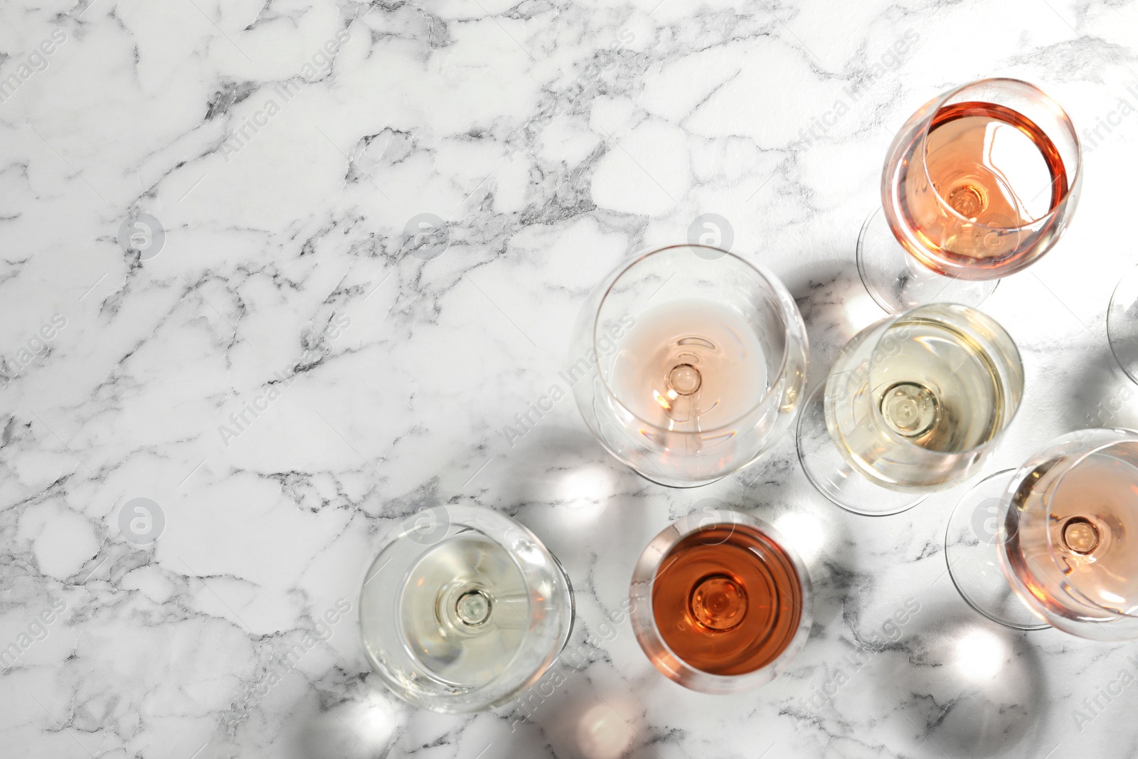 Photo of Different glasses with wine on marble background, flat lay. Space for text