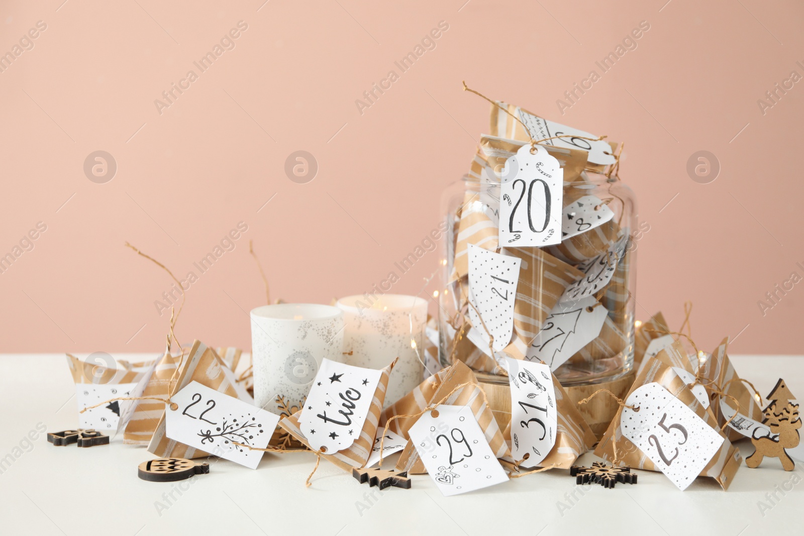 Photo of Christmas advent calendar with small gifts and burning candles on white table