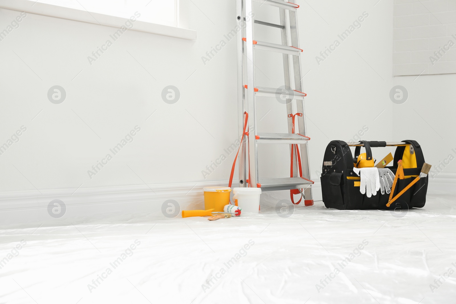 Photo of Stepladder and different tools near wall in room. Interior renovation