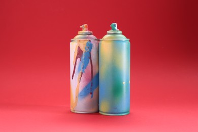 Photo of Two spray paint cans on red background