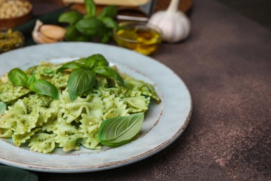 Photo of Delicious pasta with pesto sauce and basil on dark textured table, closeup. Space for text