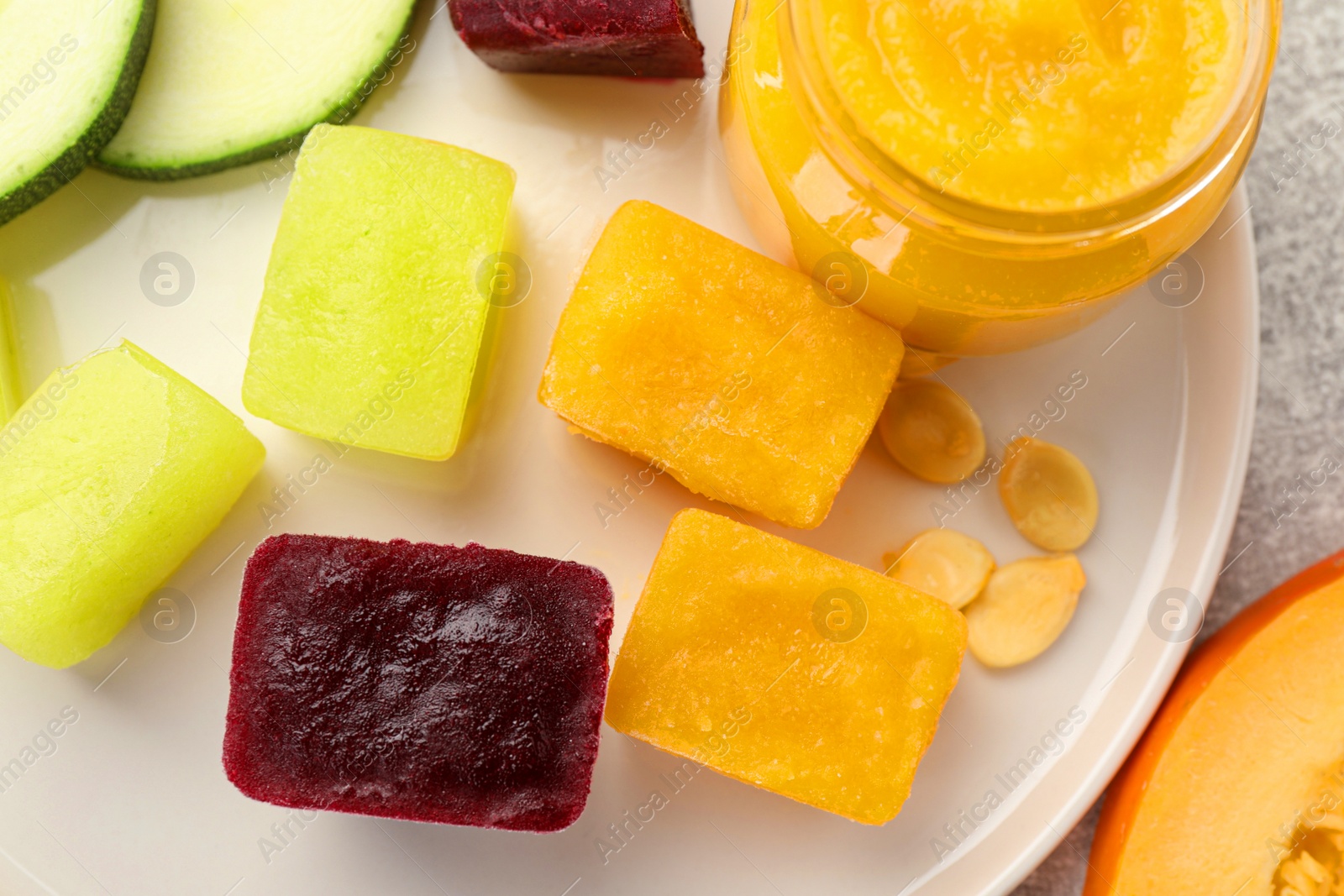 Photo of Frozen beet, pumpkin and zucchini puree cubes on plate, top view