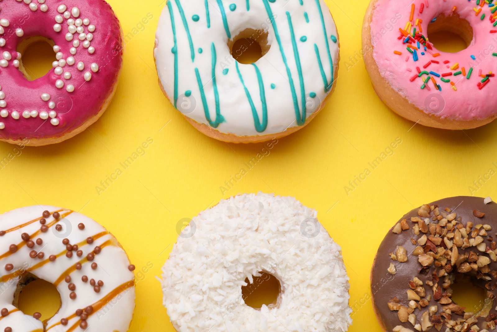 Photo of Tasty glazed donuts on yellow background, flat lay