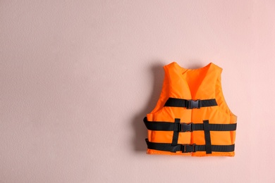 Photo of Orange life jacket on pink background. Space for text
