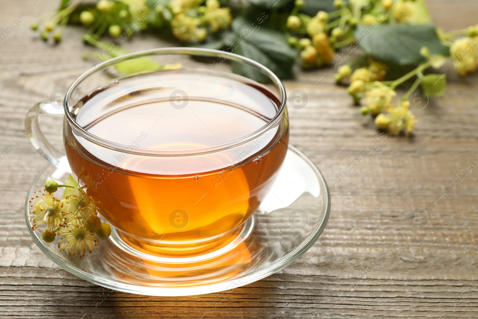 Photo of Cup of tea and linden blossom on wooden table. Space for text