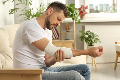 Man with arm wrapped in medical bandage at home