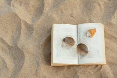 Photo of Beautiful sunglasses, book and shell on sand, top view. Space for text