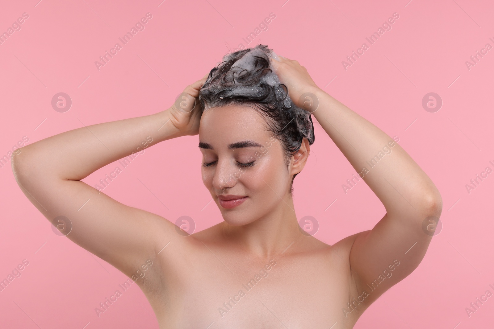 Photo of Portrait of beautiful happy woman washing hair on pink background