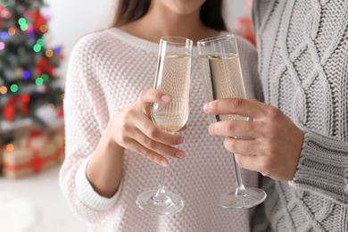 Photo of Happy young couple with glasses of champagne celebrating Christmas at home