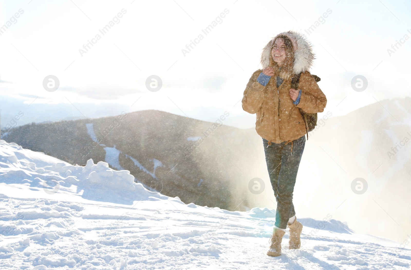 Photo of Happy young woman with backpack spending winter vacation in mountains. Space for text