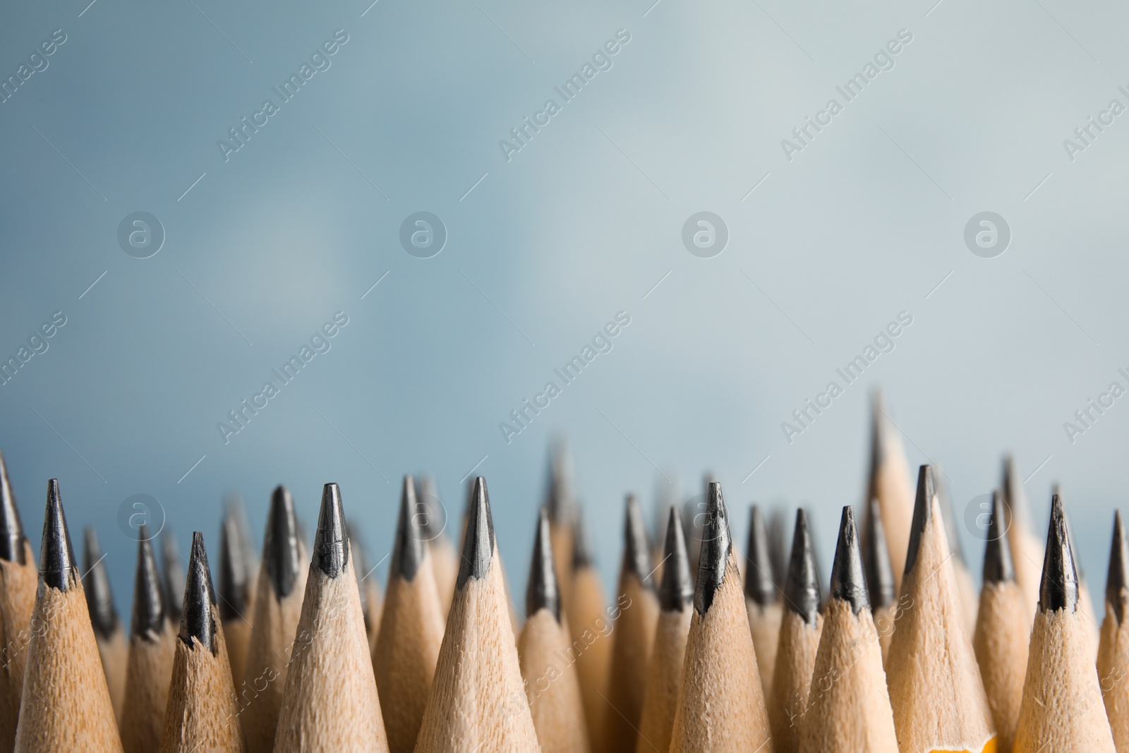 Photo of Many graphite pencils on blue background, closeup. Space for text