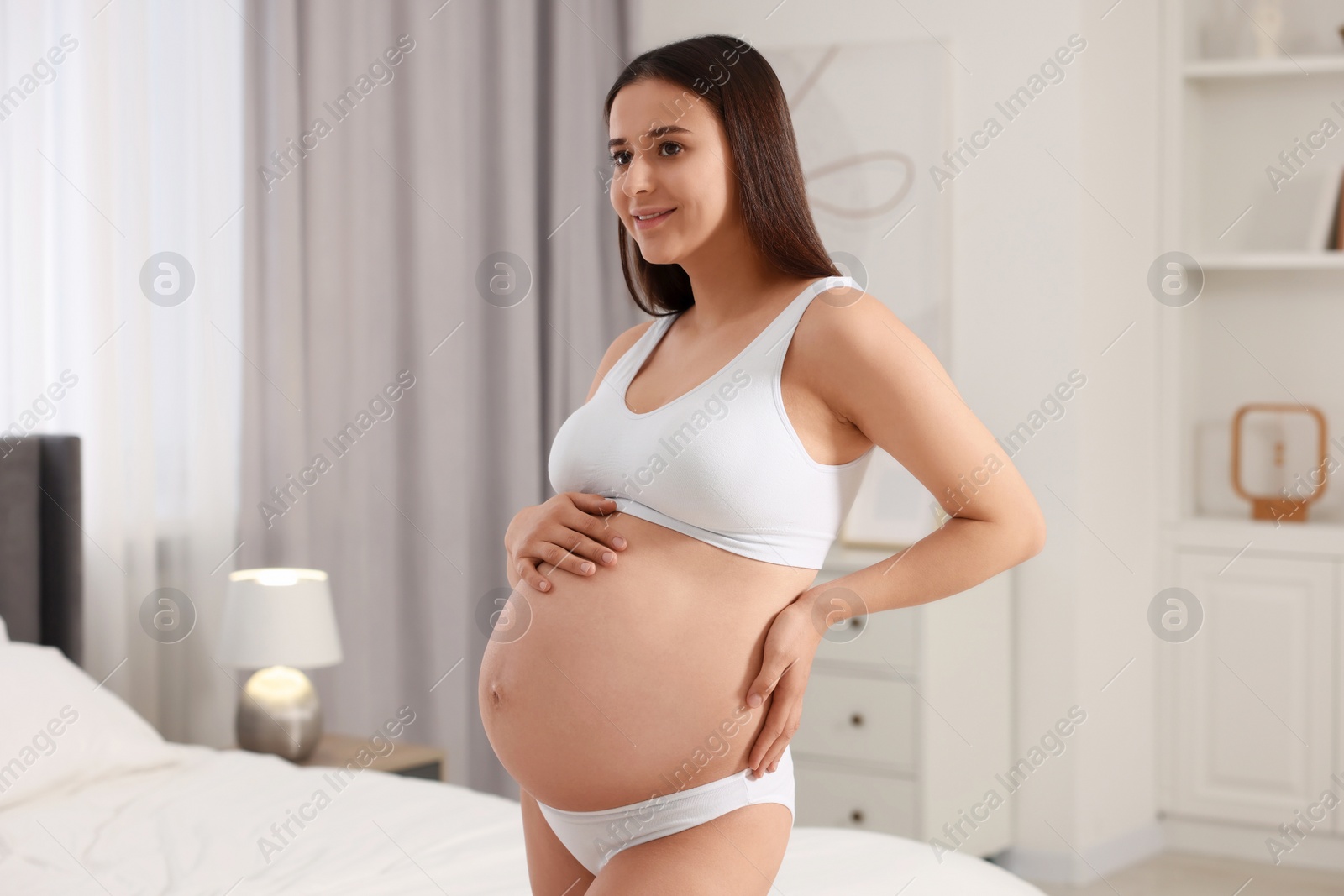 Photo of Beautiful pregnant woman wearing stylish comfortable underwear in bedroom