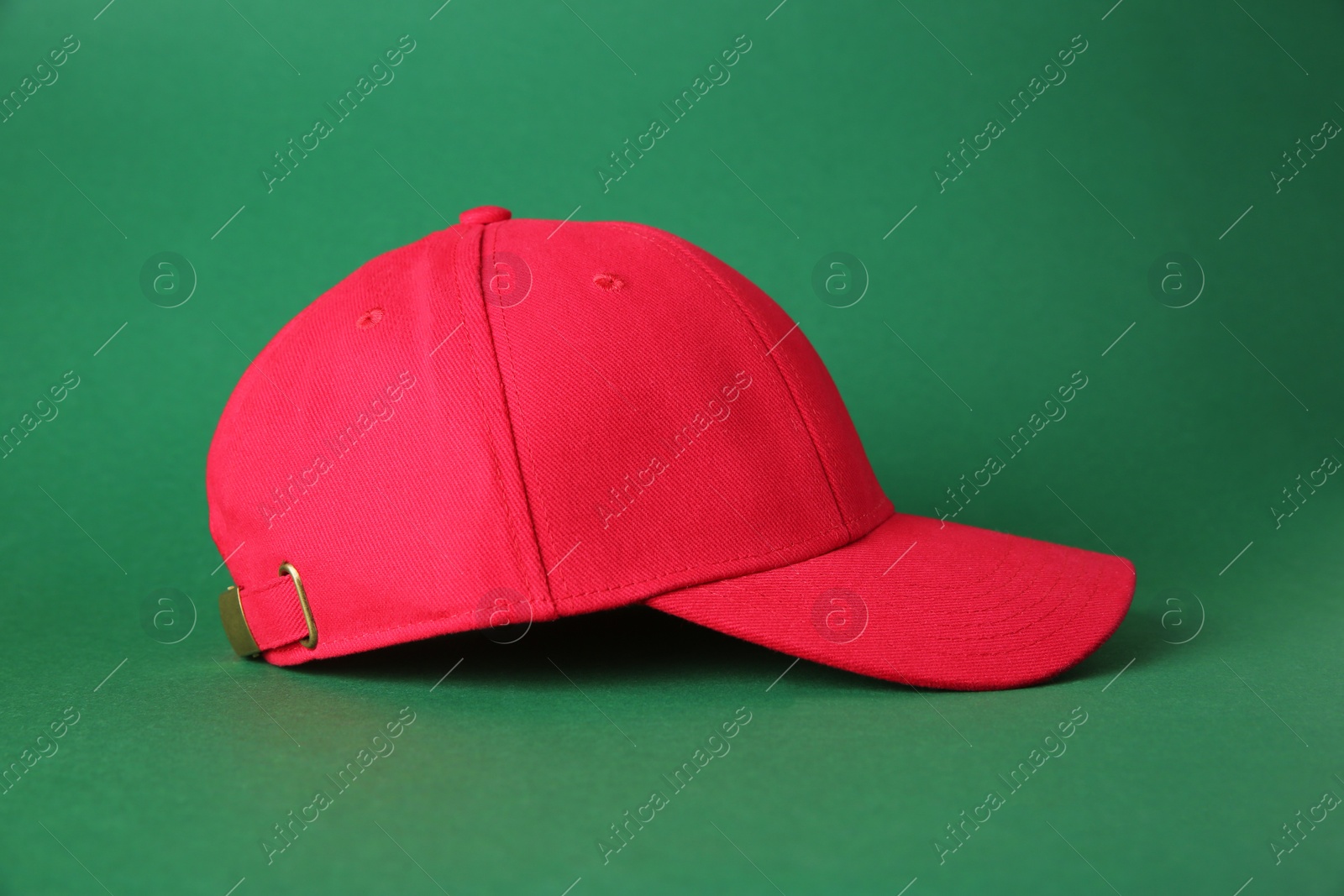 Photo of Stylish red baseball cap on green background