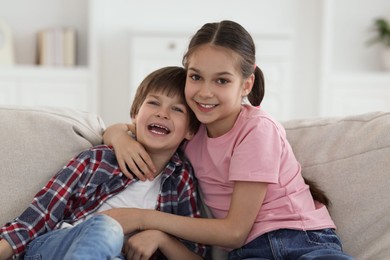 Photo of Happy brother and sister spending time together on sofa at home