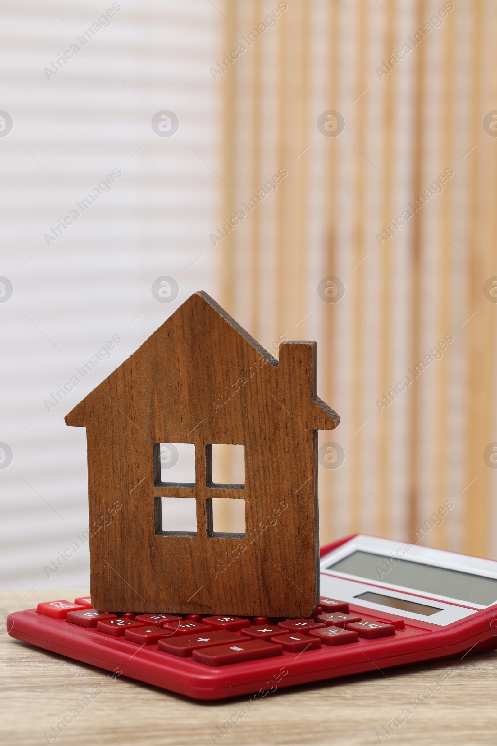 Photo of House model and calculator on wooden table