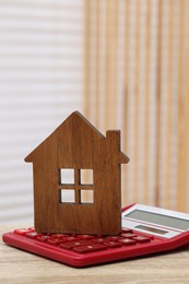 House model and calculator on wooden table