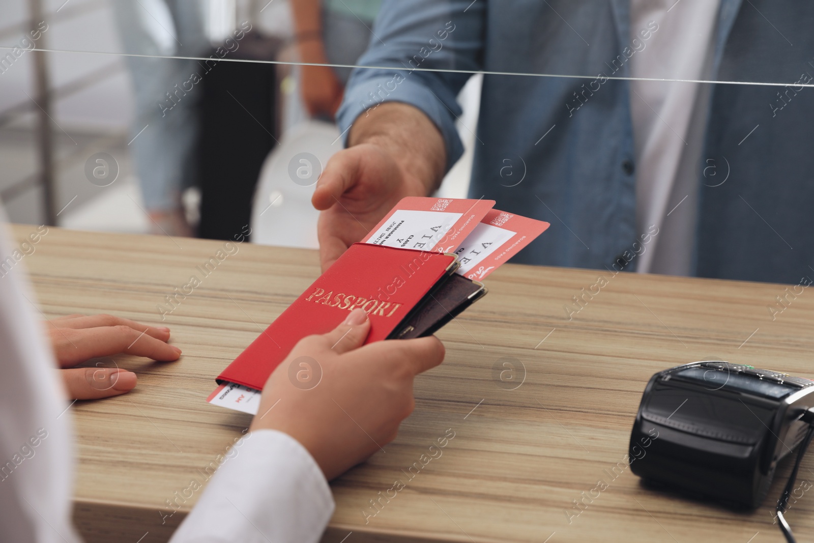 Photo of Agent giving passports with tickets to client at check-in desk in airport, closeup