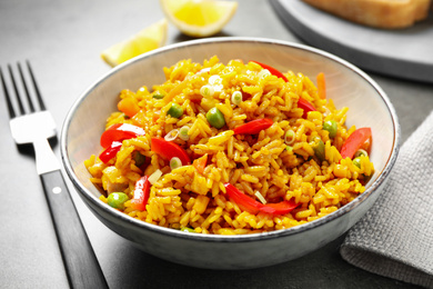 Photo of Delicious rice pilaf with vegetables on grey table