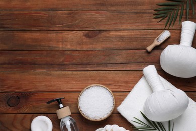 Flat lay composition of herbal bags and spa products on wooden table, space for text