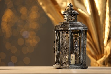 Arabic lantern on table against blurred lights, space for text