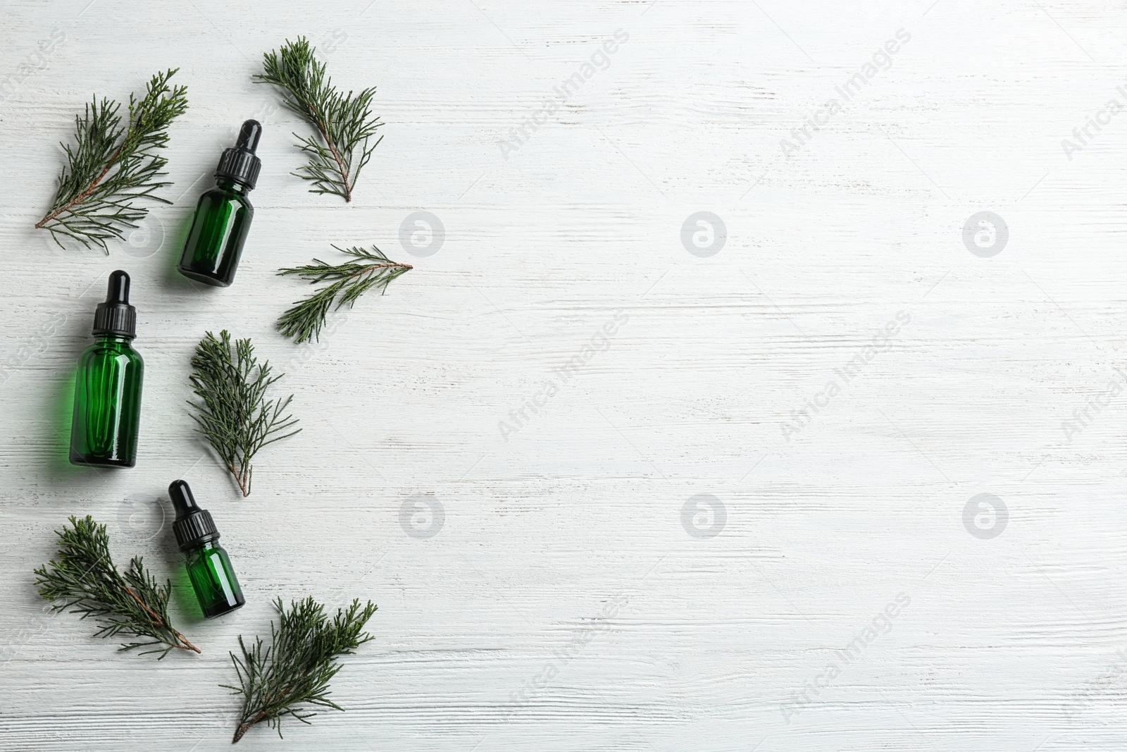 Photo of Flat lay composition with bottles of conifer essential oil and space for text on white wooden background